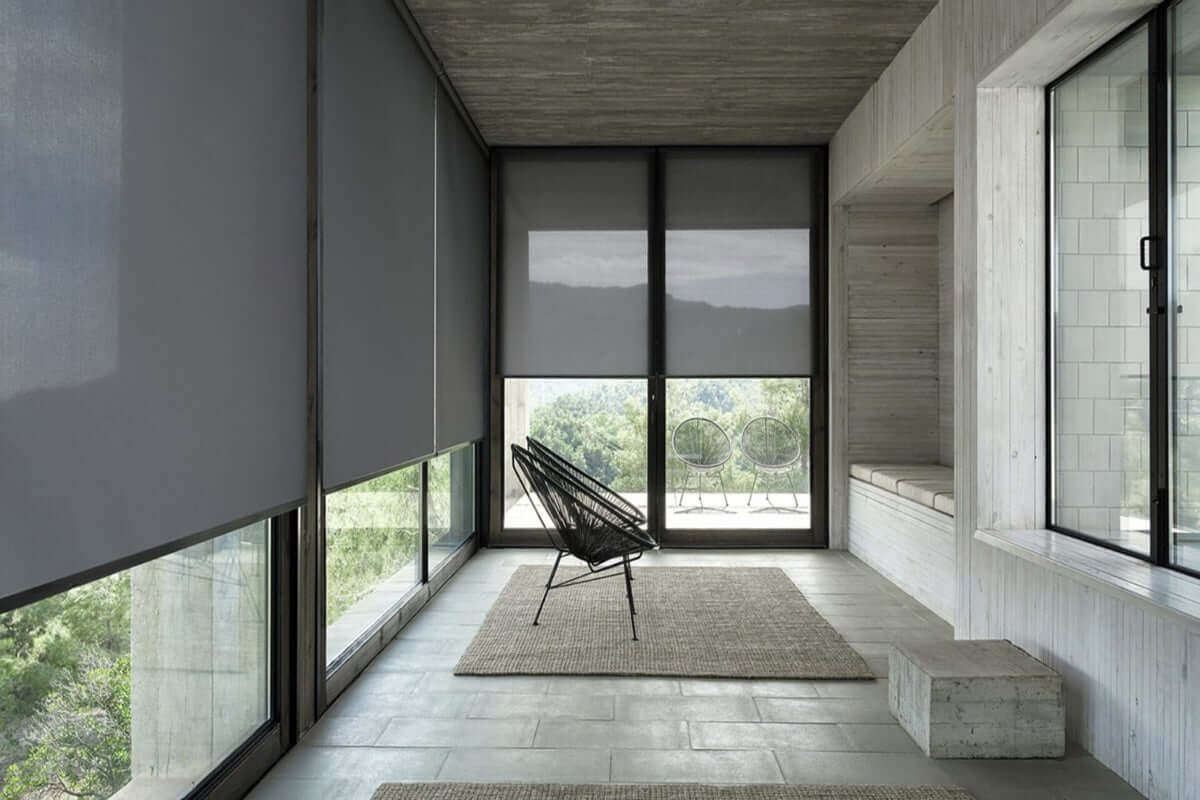 Store enroulable sur mesure dans un intérieur moderne avec lumière naturelle et fauteuil confortable.