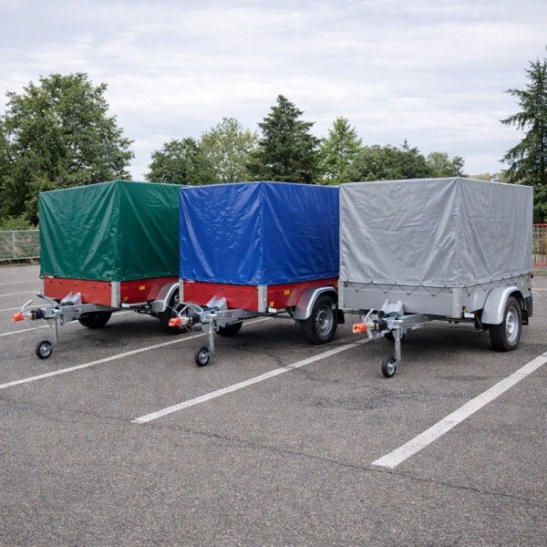 Trois remorques bâchées en vert, bleu et gris sur un parking